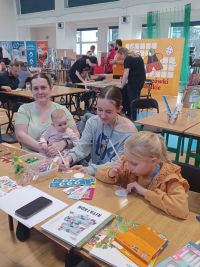 Uczestnicy Festiwalu Gier Planszowych i Komiksu przy stoisku biblioteki.