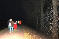 Grupa osób idzie po parku nocą.