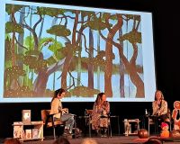 Trzy kobiety na scenie prowadzą rozmowę. W tle telebim z ilustracją z ksiązki