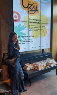 Kobieta na tle telebimu z nazwą konferencji