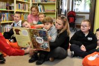 Grupa dzieci ogląda książkę ,,Rok w lesie".