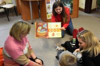 Bibliotekarka pokazuje dzieciom książkę o ptakach.