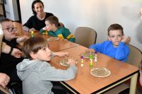 Grupa chłopców siedzi przy stolikach, przed nimi prace plastyczne, przedstawiające ptasie gniazdka.