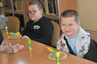 Dwóch chłopców siedzi przy stoliku, przed nimi papierowe ptasie gniazdka i ptaszki.