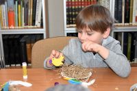 Chłopiec trzymający w ręku papierowego ptaszka.