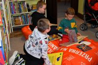 Grupa chłopców na pufach w bibliotece, oglądają książki.