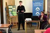 Młody chłopak stoi na sali bibliotecznej i przemawia