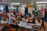 Grupa dzieci przy stolikach w sali lekcyjnej