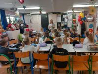 Grupa dzieci przy stolikach w sali lekcyjnej