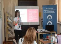 Kobiety siedzące przy stolikach, na których znajdują się kosmetyki.