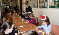 Dzieci wykonujące własnoręcznie ozdoby bożonarodzeniowe na świątecznych warsztatach w bibliotece.