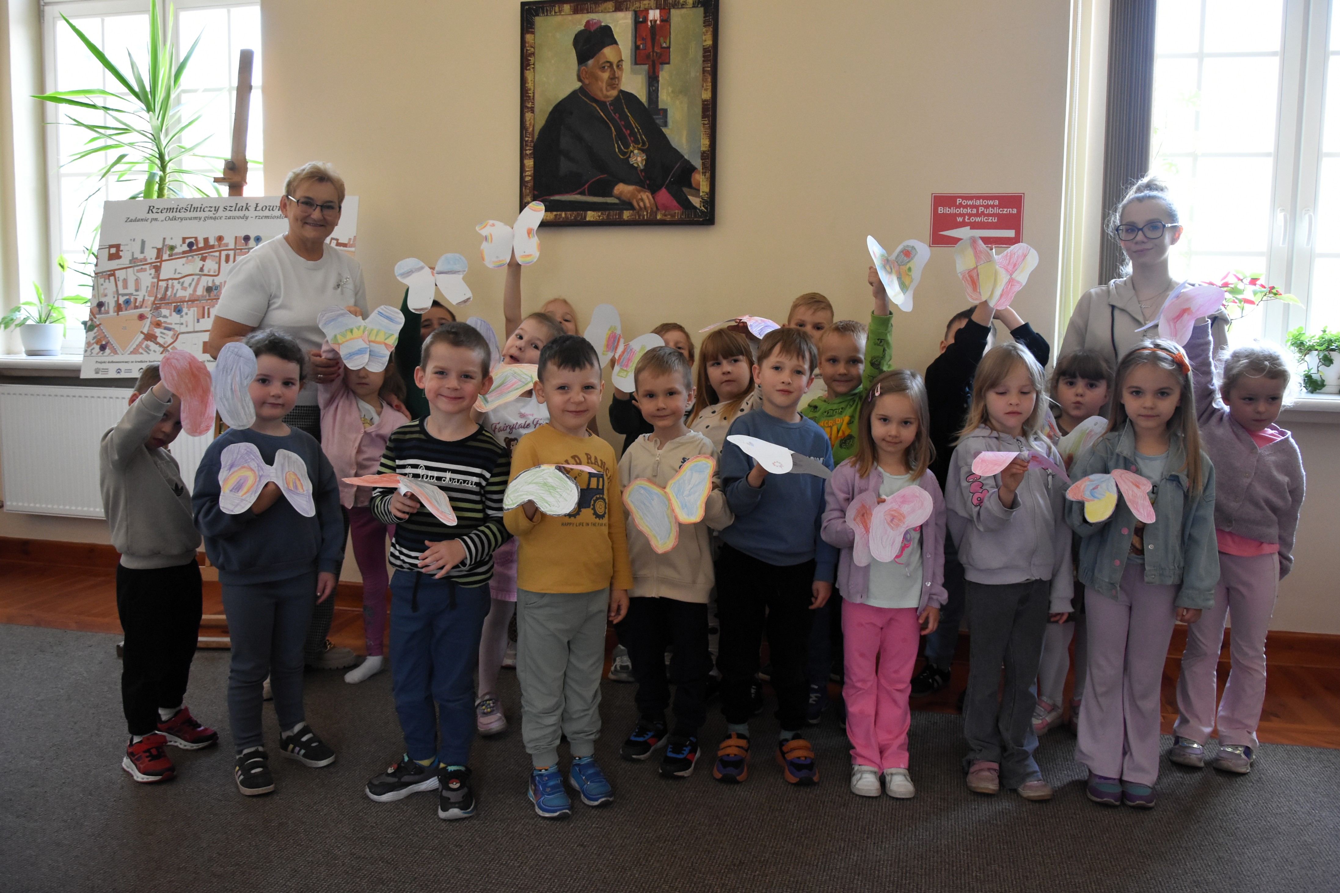 Grupa przedszkolaków w bibliotece pozuje do zdjęcia.